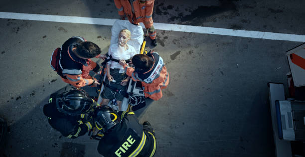 Paramedic team stabilizing injured woman on stretcher at scene of accident Paramedic team stabilizing woman involved in car accident lying on stretcher. stretcher stock pictures, royalty-free photos & images