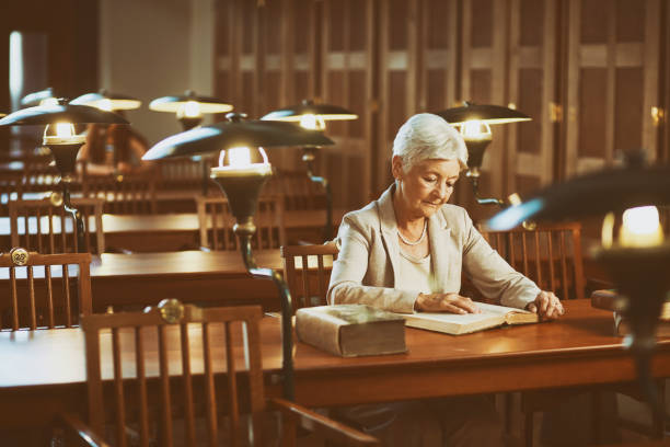 istock Senior woman reading an old book in the library 1045865666