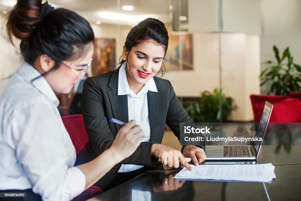 Signing a contract Indian female agent helping client sign the application document Banking Stock Photo