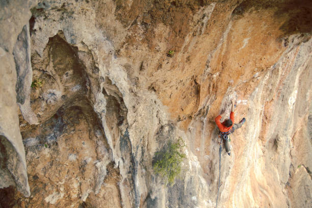 istock Man rock climber. Rock climber climbs on a rocky wall. Man makes hard move. 1045877224