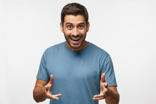 istock Come on! Let's do it! Young man in blue t-shirt shouting, looking at camera with wide opened mouth, gesturing with both hands 1045886584