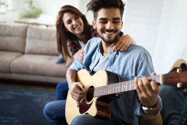 istock Young handsome man playing guitar for his girlfriend 1045890876