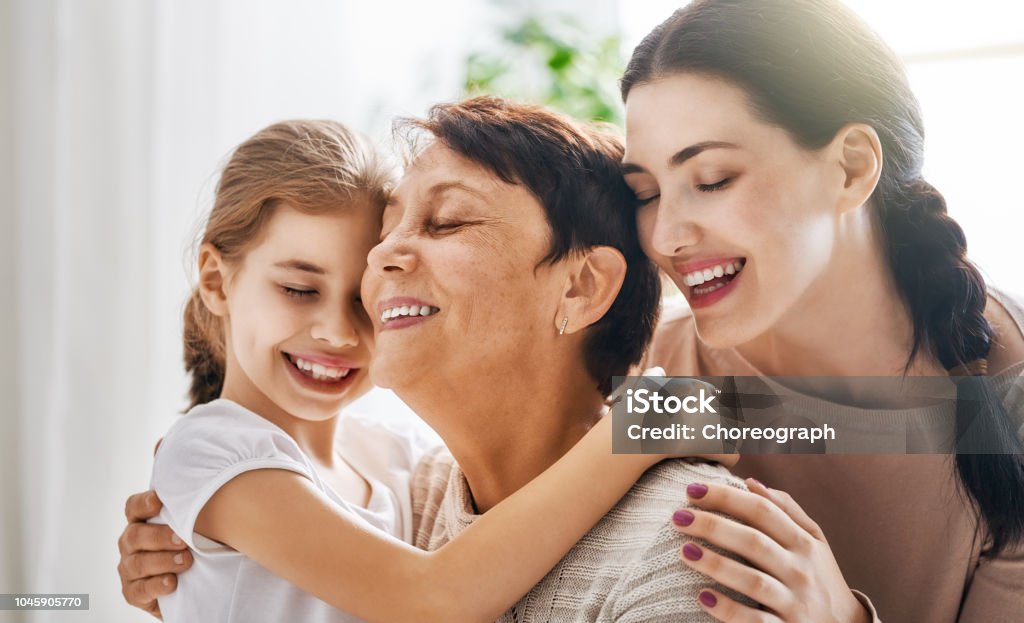 girls, their mother and grandmother A nice girl, her mother and grandmother enjoy sunny morning. Good time at home. Family playing in the bedroom. Mother Stock Photo