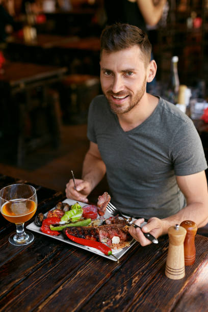 istock Restaurant. Man Eating Food With Beer At Cafe. 1045905876