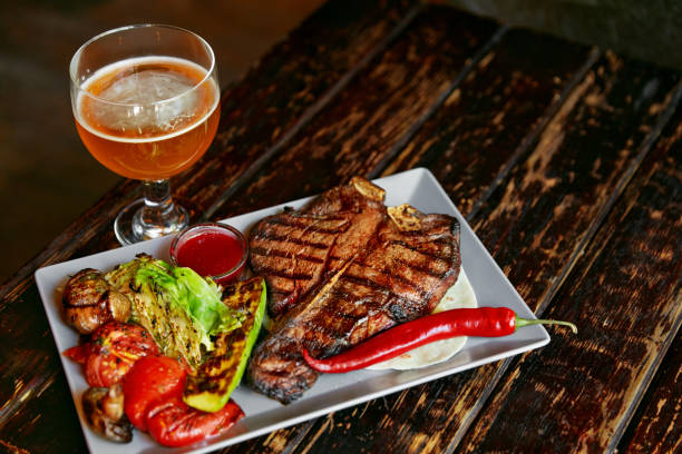 istock Steak And Beer. Barbecue Meat With Grill Vegetables And Beer 1045906842