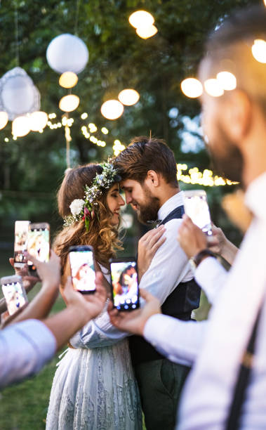 clientes con smartphones tomando foto de novios en el banquete fuera. - men groom wedding red fotografías e imágenes de stock