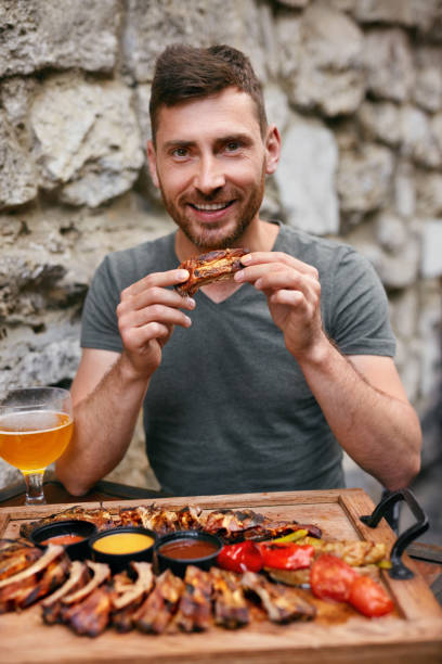 istock Man Eating Barbecue Meat With Beer 1045917990