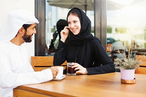Happy middle eastern man talking to a woman over cup of coffee