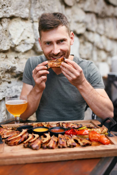 istock Steak-house. Handsome Man Eating Barbecue Ribs With Beer 1045922290