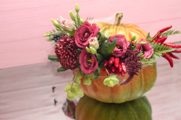 istock Halloween pumpkin with flowers and leaves on mirrow table 1045922478