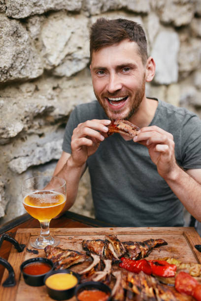 istock Steak-house. Handsome Man Eating Barbecue Ribs With Beer 1045922490