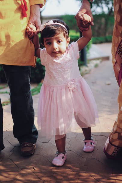 istock Toddler learning to walk holding hands 1045922572
