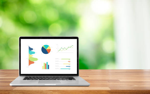 istock Modern laptop on wooden table showing charts and graph against s blurred blue modern buildings and sky background 1045942080