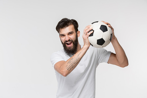Young soccer player with ball in front of white studio background