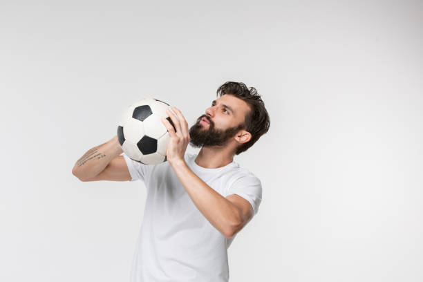 Young soccer player with ball in front of white studio background