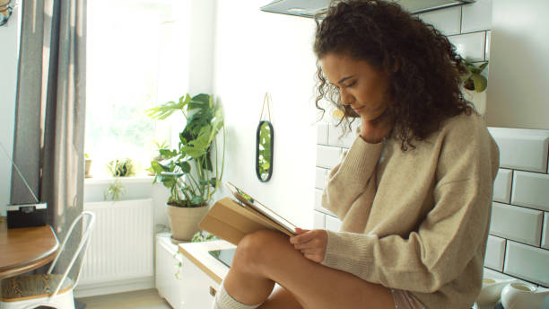 istock Pretty young woman using digital tablet in cozy kitchen. 1045960510