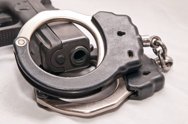 istock A pair of black and silver handcuffs draped over a black pistol 1045975620