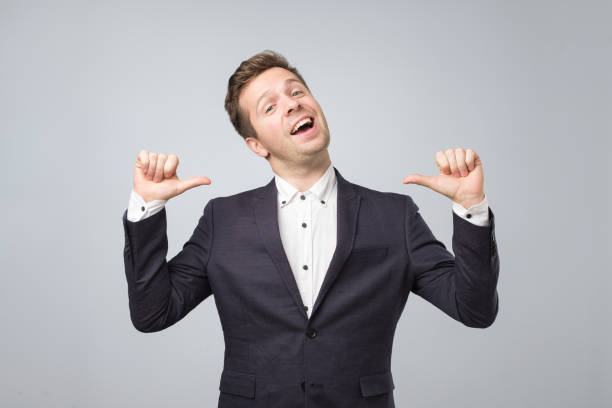 Very proud man shows his fingers on himself standong isolated on lgray background. Very proud man shows his fingers on himself standong isolated on lgray background. Handsome businessman is happy that he managed to conclude a bargain arrogance stock pictures, royalty-free photos & images