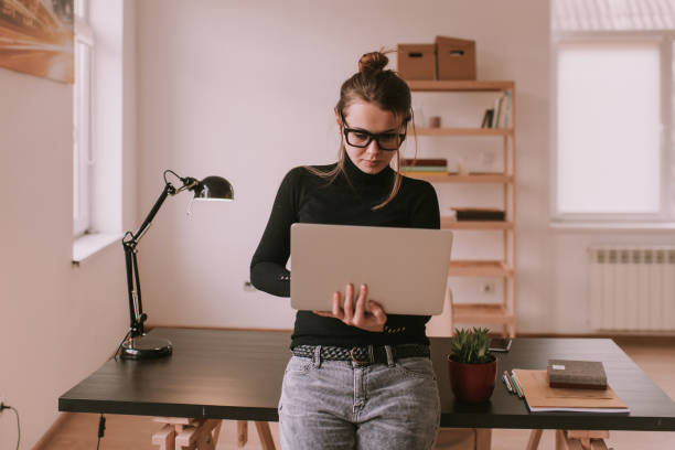 istock Girl in office working with laptop standing near table 1045990520