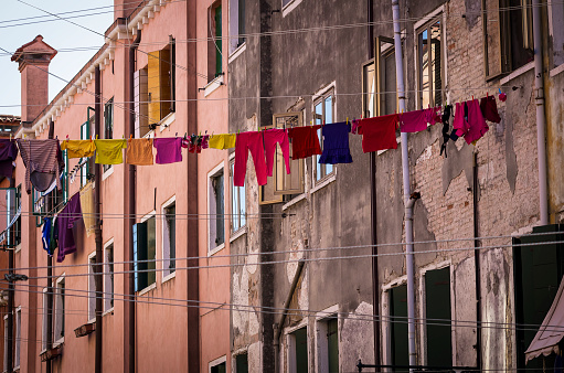 A clothesline in Venice with bright colourful clothing, with an old textured building in the background.