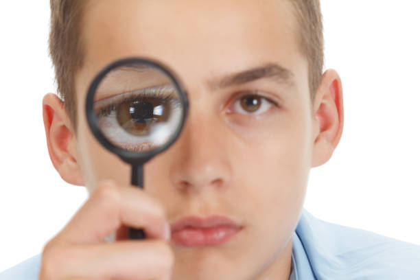 istock Funny Child schalit with a magnifying glass at School. 1046024064