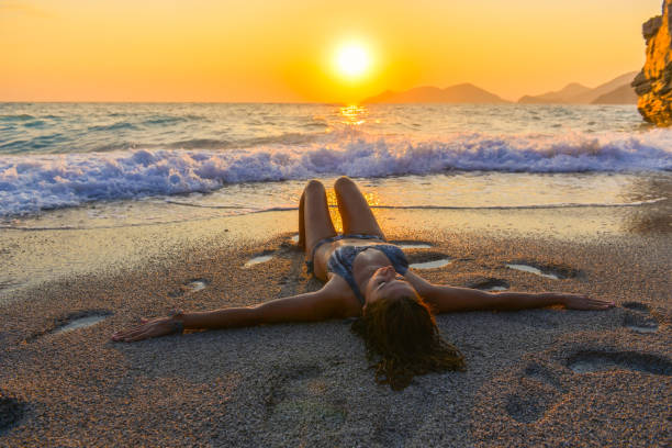 Woman is among the waves at sunset.