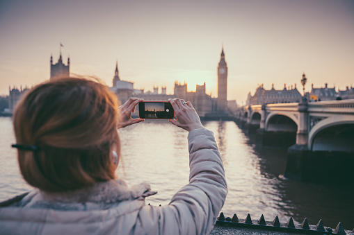Rear view of woman photographing London landmarks with mobile phone