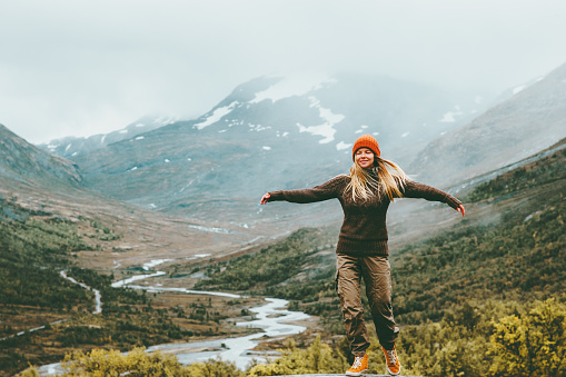 Woman bliss emotional raised hands foggy mountains on background Travel Lifestyle wellness concept adventure  vacations outdoor harmony with nature Jotunheimen park in Norway