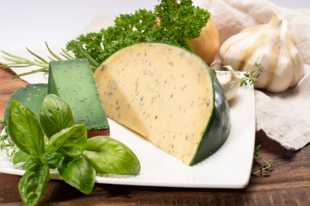 fromage à pâte dure spécialité néerlandaise fait de lait de vaches avec différentes épices et herbes vertes fraîches - basiron photos et images de collection