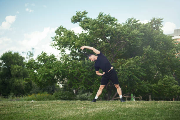 istock Attractive young man doing stretching exercises with hands outdoor in park. 1046080402