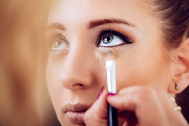 Perfect Makeup Makeup artist applying concealer on a beautiful young woman's face. Close up. concealer stock pictures, royalty-free photos & images