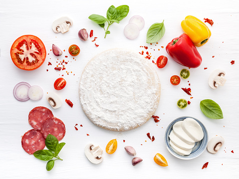 The ingredients for homemade pizza on white wooden background.The ingredients for homemade pizza on dark stone background.