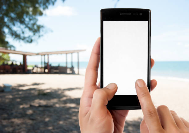 istock hand hold and touch screen smart phone,over blurred beautiful beach background 1046098690