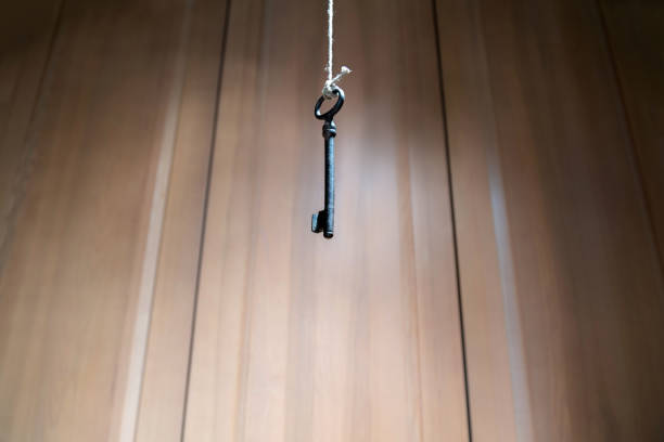 istock Looking up at old key hanging on string. Vintage wooden background 1046116498