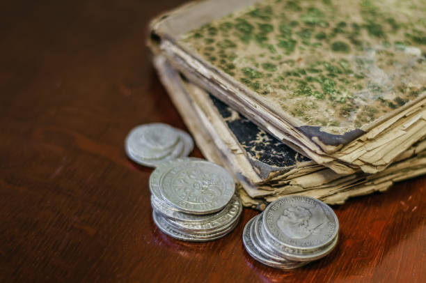istock Old worn books with yellow sheets. Medieval coins are thalers on the table. 1046119330