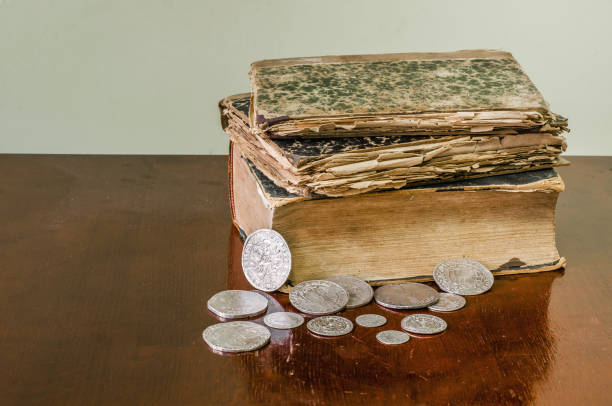 istock Old worn books with yellow sheets. Medieval coins are thalers on the table. 1046119350