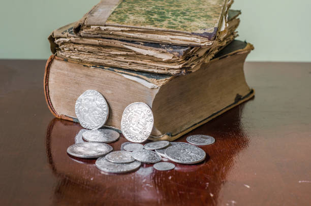 istock Old worn books with yellow sheets. Medieval coins are thalers on the table. 1046119358