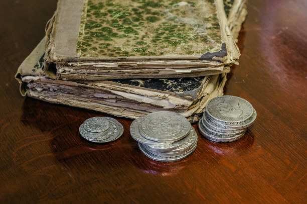 istock Old worn books with yellow sheets. Medieval coins are thalers on the table. 1046119372