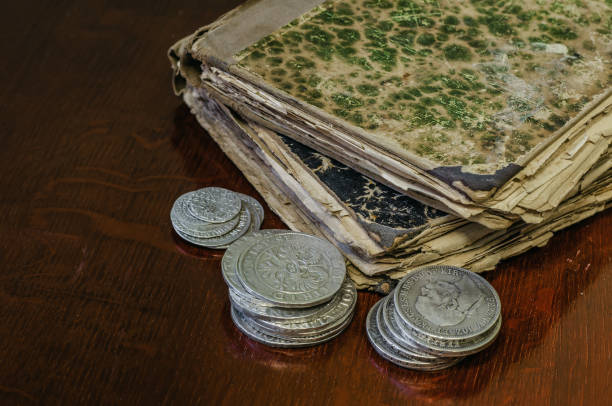 istock Old worn books with yellow sheets. Medieval coins are thalers on the table. 1046119382