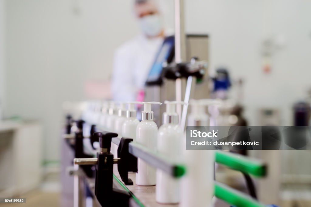 Picture of lotion bottles on production line. Bottles of cosmetic products in factory production line. Manufacturing Stock Photo