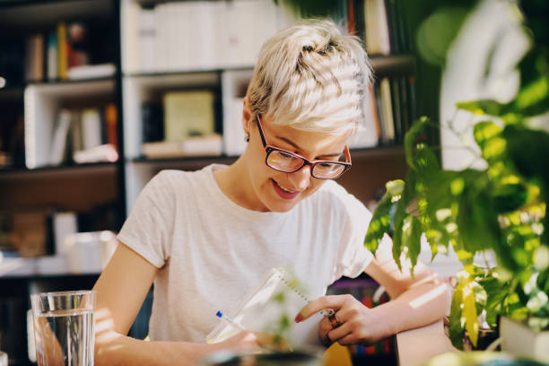 istock Cute hard working student girl sitting in a library and taking notes. 1046124144