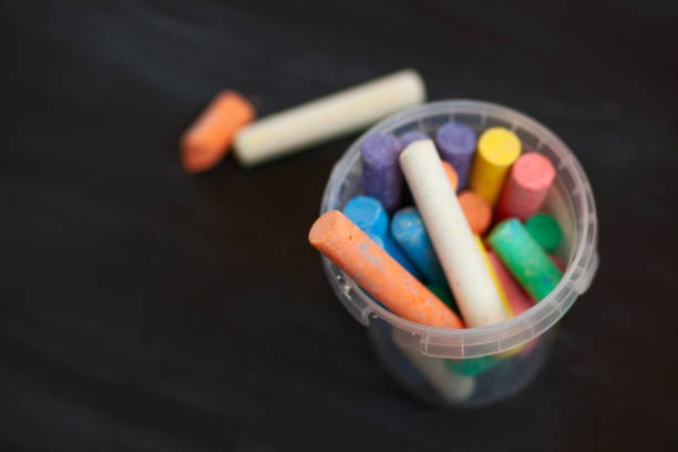 istock Color chalk in plastic cans closeup on blackboard. Selective focus 1046133108