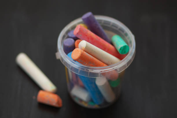 istock Color chalk in plastic cans closeup on blackboard. Selective focus 1046134184