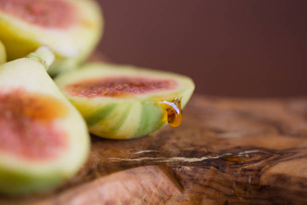 Tiger Stripe Figs dripping rich dark organic honey served on top of an olive wood cutting board.‘Panache Tiger Fig’ is a paragon of beauty and taste. Fig tree’s delicious small-to-medium-sized green fruits are beautifully patterned with yellow tiger stripes. Scrumptious fruits, with aromatic, highly flavorful blood-red flesh, make for fine fresh eating; add nectary sweetness to salads and cereals; and, partnered with fresh quince, is the stuff of which superb jams and pies are made.