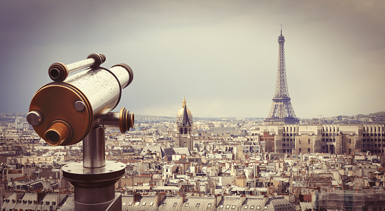 Retro telescope with panoramic view of Eiffel tower and Paris cityscape