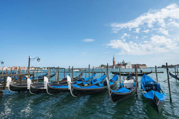 Venice, Italy – August 30, 2018: Pier with anchored Gondolas at the Canal Grande. The  church of San Giorgio Maggiore is in the background
