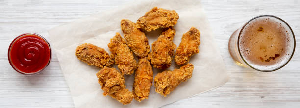 istock Chicken wings with sauce, cold beer on a white wooden table, overhead. 1046145986