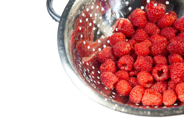 istock Delicious fresh and wet red raspberry in a colander for washing isolated at white background 1046149080
