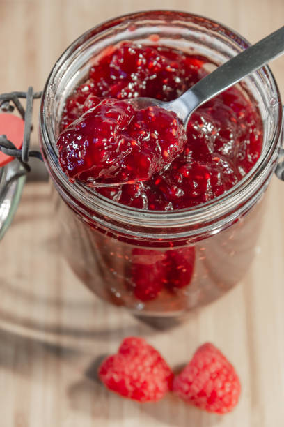 istock Red raspberry jam in glass and fresh raspberries with a spoon 1046149498