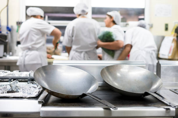 istock Two silver big frying pans with four kitchen workers in a restaurant 1046149998